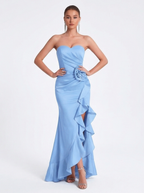 Woman wearing a light blue strapless gown with floral details on a white background