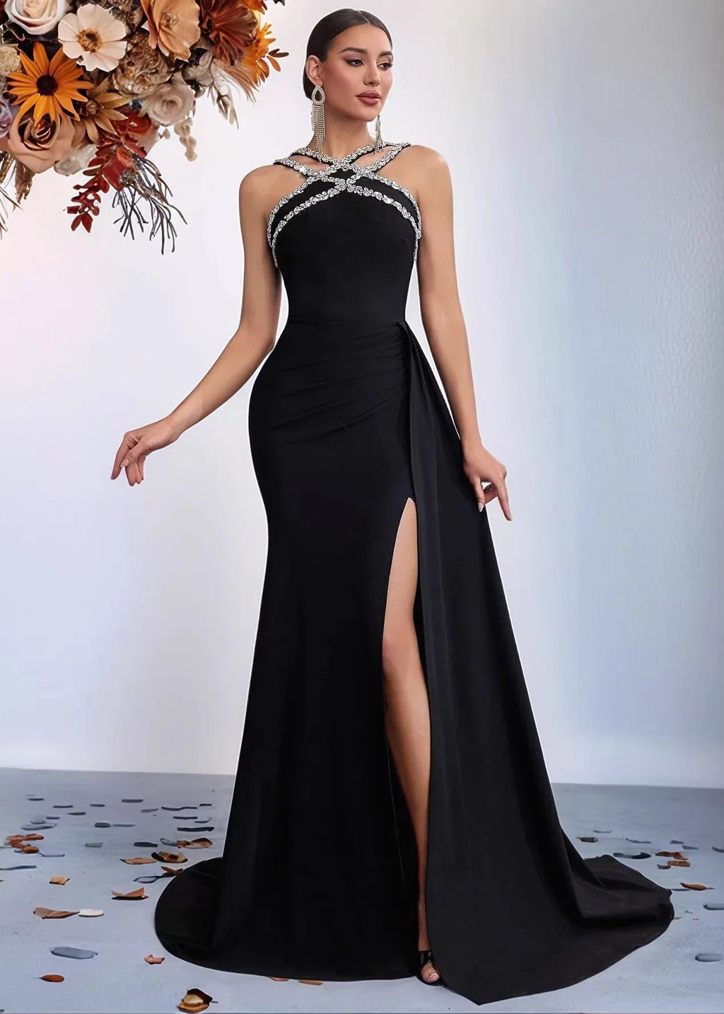 Woman in a black evening gown with a high slit, standing against a plain background.
