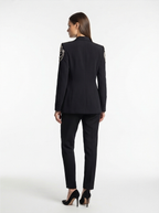 Woman wearing a black suit with decorative elements on a white background
