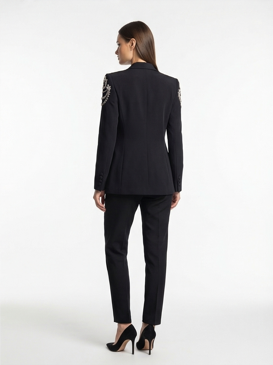 Woman wearing a black suit with decorative elements on a white background