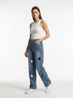 Woman wearing blue jeans with heart patches on a white background