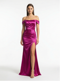 Woman wearing a vibrant pink off-shoulder gown with a high slit on a white background