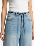 Light blue denim pants with a white top on a plain background