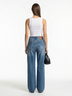 Woman wearing blue jeans and a white top on a white background
