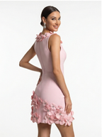 Woman wearing a pink dress with floral embellishments on a white background
