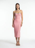 Woman wearing a pink strapless dress with embellishments on a white background