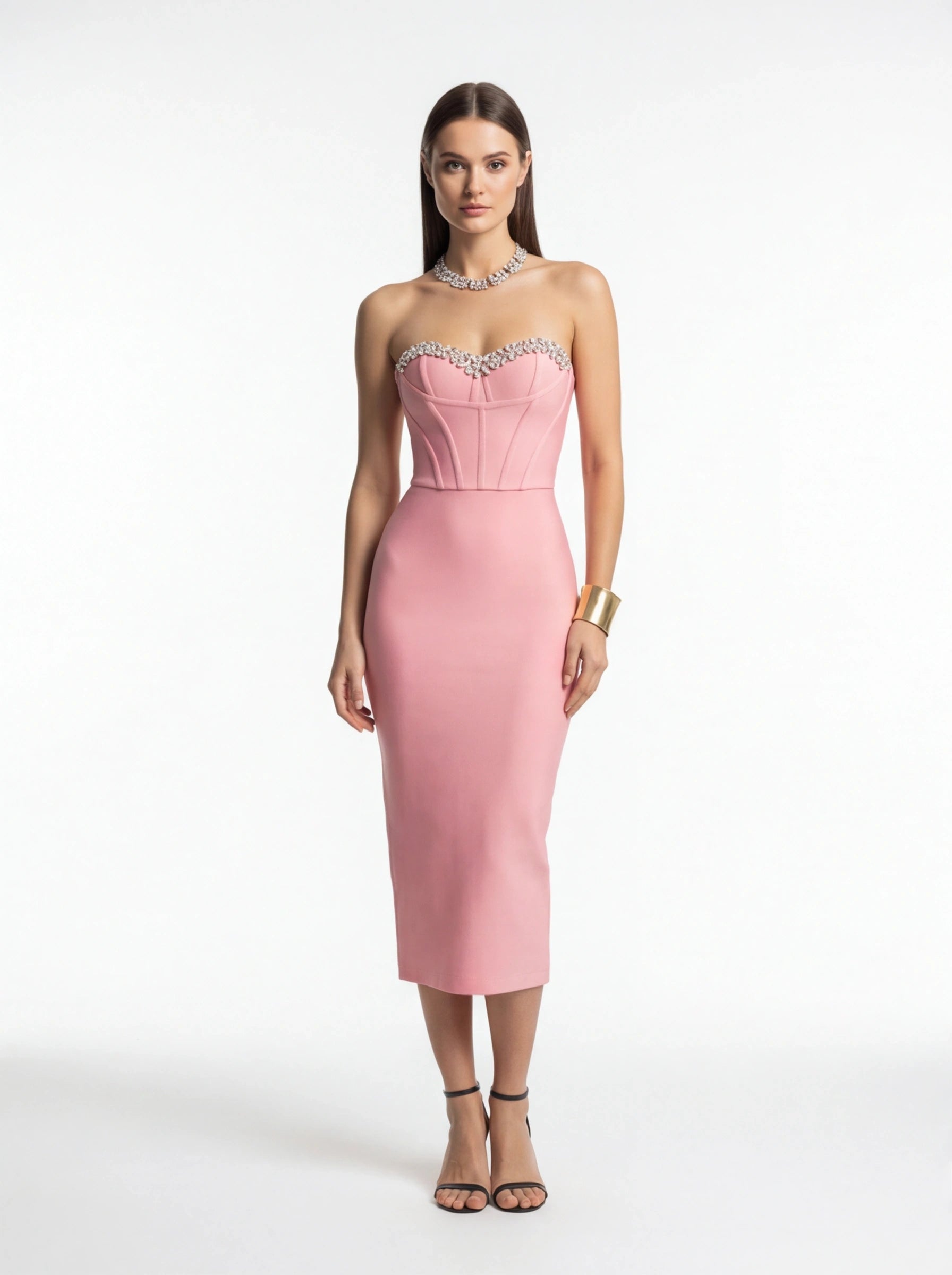 Woman wearing a pink strapless dress with embellishments on a white background