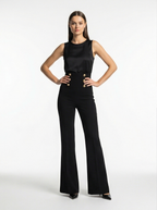 Woman wearing a black sleeveless top and black pants on a white background