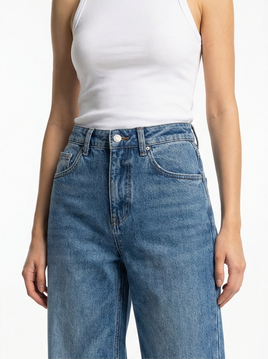 Person wearing blue jeans and a white tank top on a plain background
