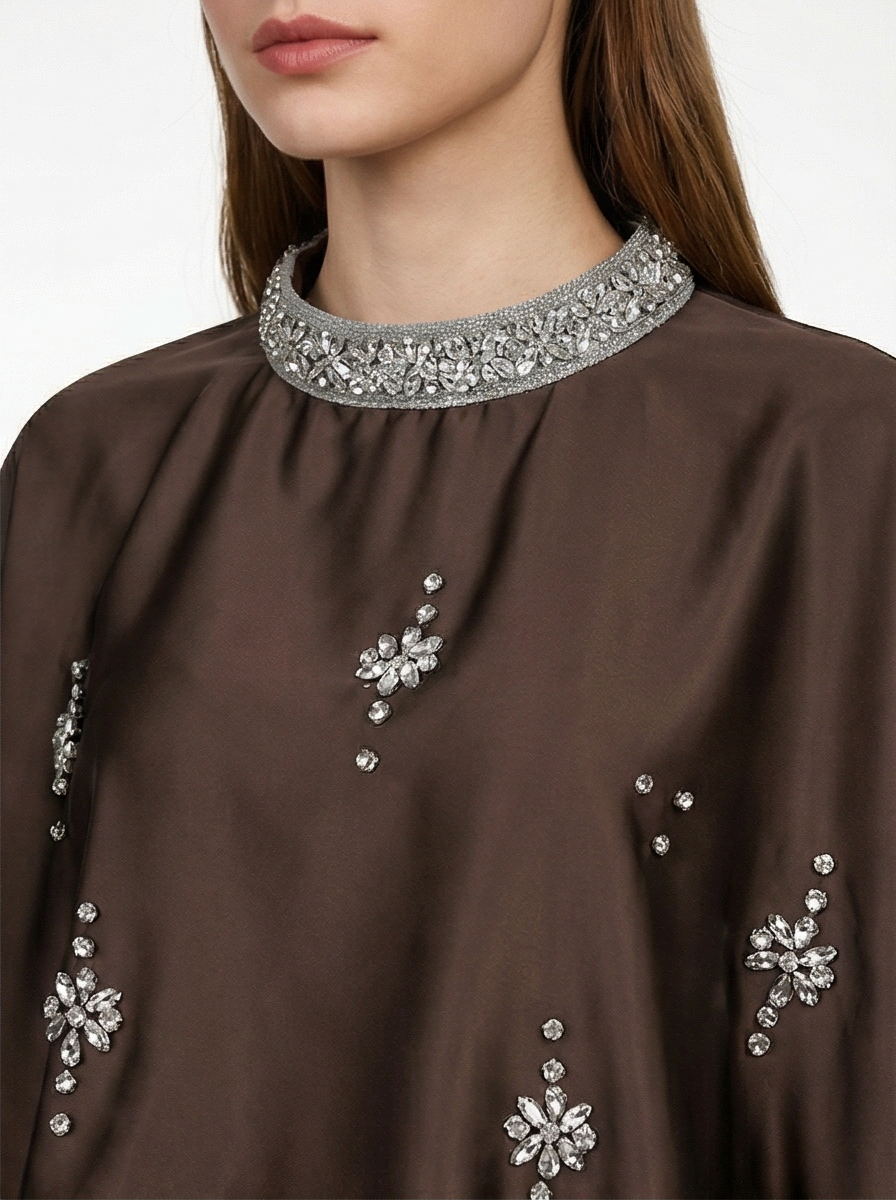 Brown garment with silver embellishments on a neutral background