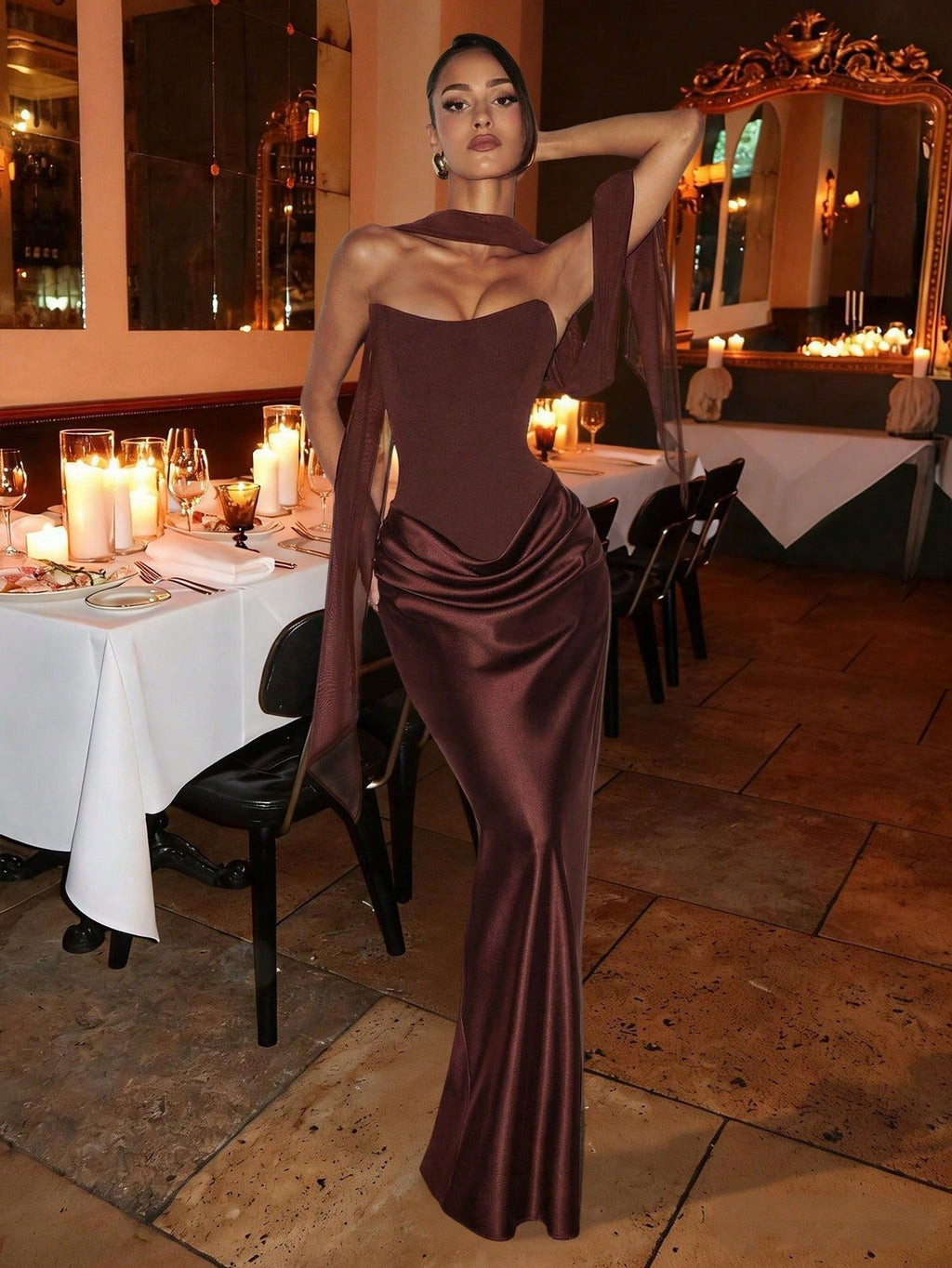 Woman in a brown dress standing in a restaurant with tables and candles in the background