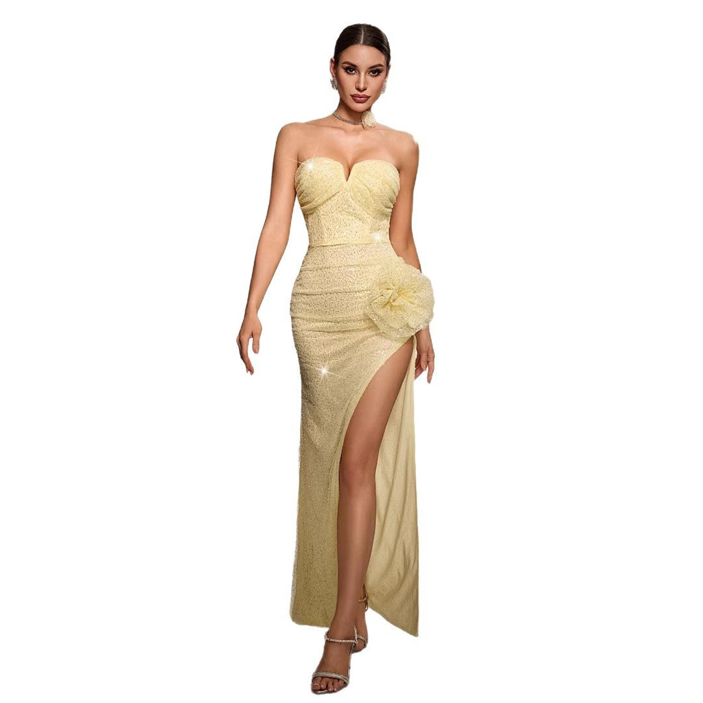 Woman wearing a strapless, high-slitted yellow evening gown on a white background