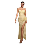 Woman wearing a strapless, high-slitted yellow evening gown on a white background