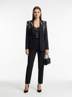 Woman wearing a black suit with floral embellishments on a white background