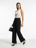 Woman wearing a white sleeveless top and black wide-leg pants on a white background