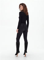 A woman shown from the back wearing a fitted black long-sleeve top, black skinny jeans, and black knee-high heeled boots with white platform soles, photographed against a clean white studio background.