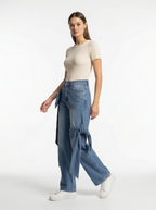 Woman wearing a beige top and blue jeans on a white background
