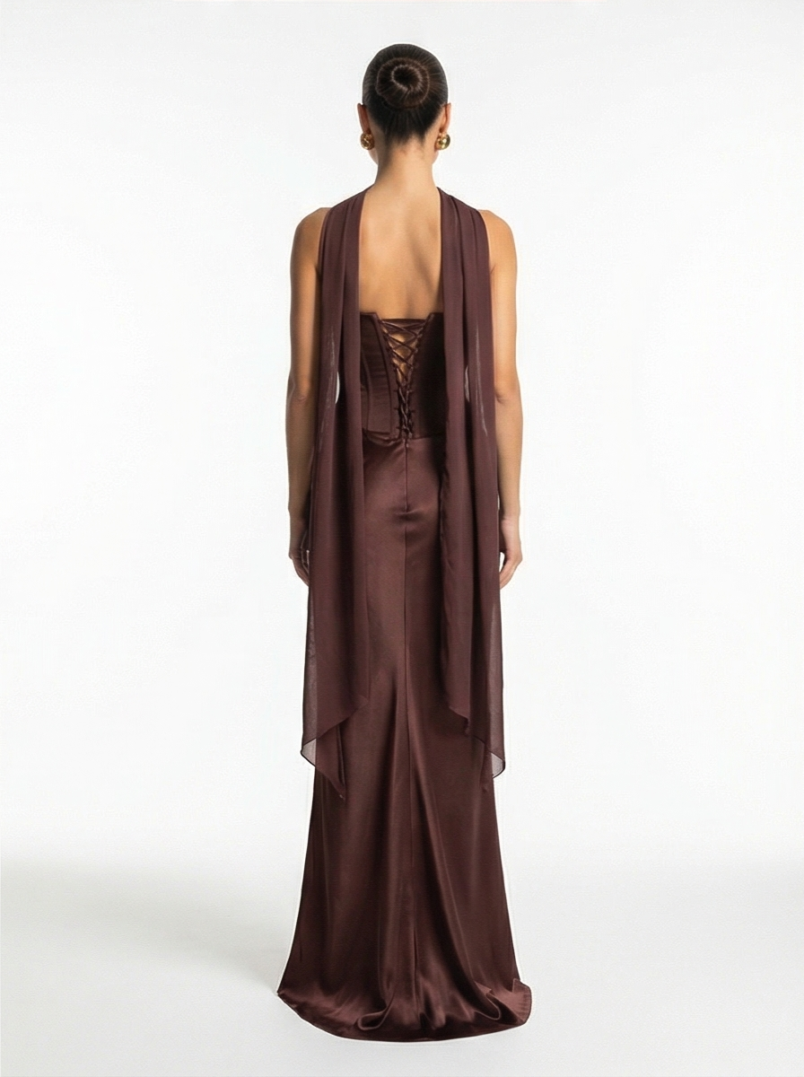 Woman wearing a brown evening gown with a sheer overlay on a white background