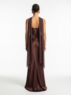 Woman wearing a brown evening gown with a sheer overlay on a white background