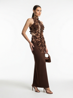 Woman wearing a brown floral evening gown on a white background