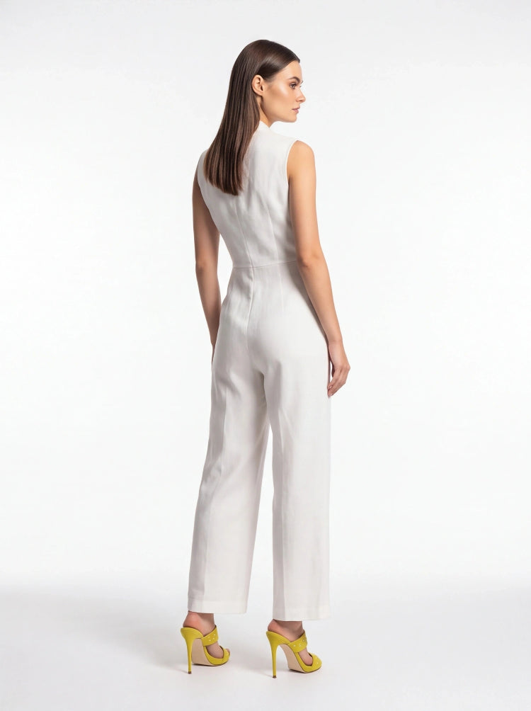 A woman modeling a white sleeveless wide-leg jumpsuit from the back, paired with bright yellow high-heeled sandals, against a plain white studio background.