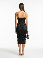 Woman wearing a black dress with ruched details on a white background