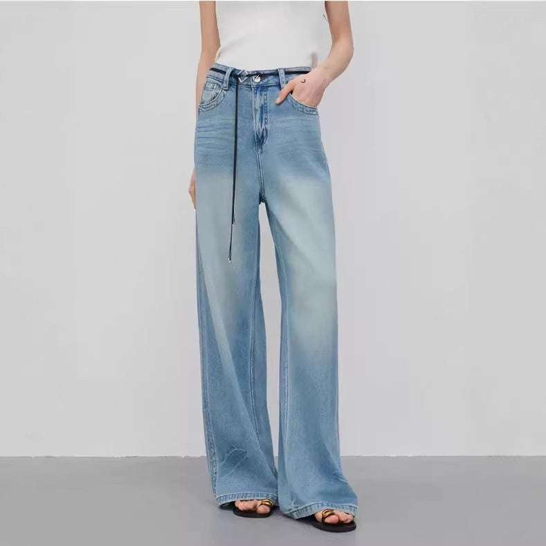 Person wearing light blue wide-leg jeans on a plain background