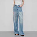 Person wearing light blue wide-leg jeans on a plain background