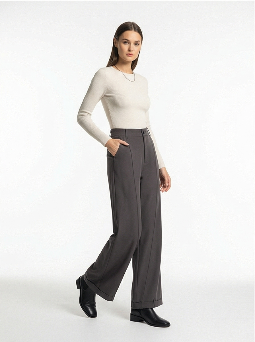 Woman wearing a white long-sleeve top and gray wide-leg pants on a white background