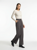 Woman wearing a white long-sleeve top and gray wide-leg pants on a white background