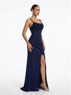 Navy blue evening gown with beaded top and slit skirt on a white background