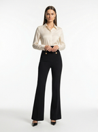 Woman wearing a white blouse and black pants on a white background