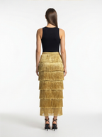 Woman wearing a black top and gold tiered skirt on a white background