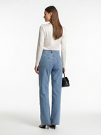 Woman wearing blue jeans and a white top on a white background