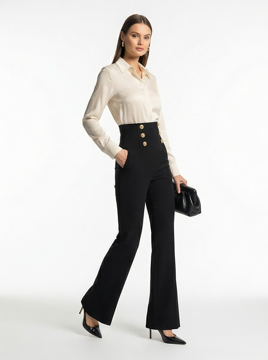 Woman wearing a white blouse and black high-waisted pants with gold buttons on a white background