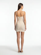 Woman wearing a beige strap dress on a white background